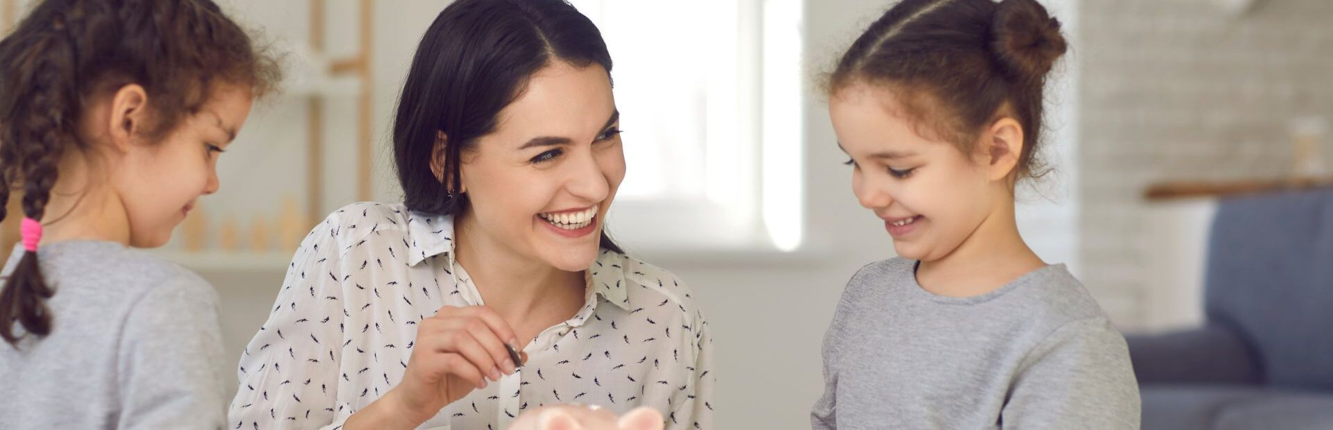 Mama ir dvi dukros meta monetą į kiaulę taupyklę